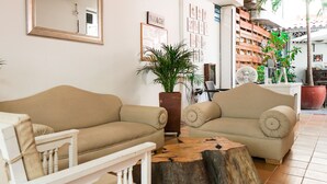 A living room with two beige sofas, a wooden coffee table, and a potted plant. - Hostal Paraiso Tayrona (Santa Marta)