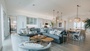 Una sala de estar moderna con un sofá modular, mesas redondas de centro y una zona de comedor con una mesa y sillas de madera.