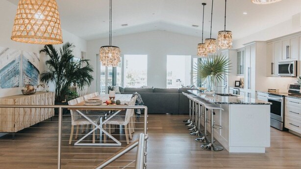 Cocina moderna con una isla central, iluminación colgante y vistas al exterior.