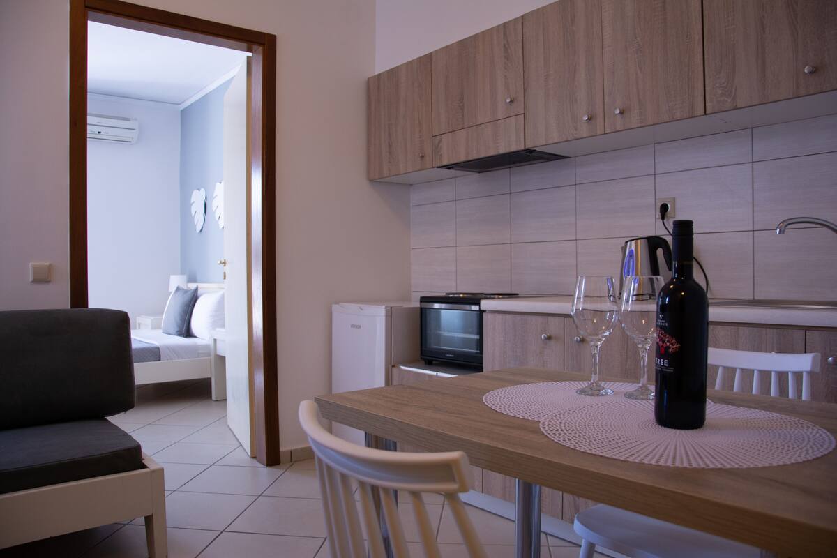 Una cocina moderna con armarios de madera, una mesa de comedor con dos sillas y un refrigerador pequeño.