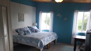 A bedroom with a bed, a desk, and a window.