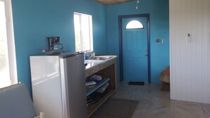 A compact kitchen with a refrigerator, sink, and window.