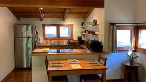 Eine kompakte Küche mit Holzbalken, einem Kühlschrank, einer Spüle und einem Essbereich mit Tisch und Stühlen.