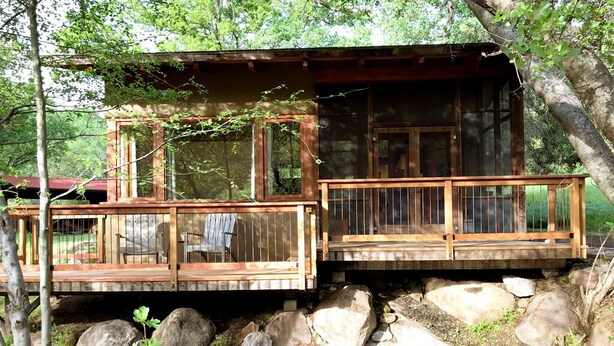 Eine Holzhütte mit einer Terrasse und einem kleinen Teich davor.