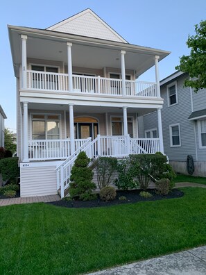 Stunning two-story residence with a central entrance, balcony, and beautifully manicured grounds.
