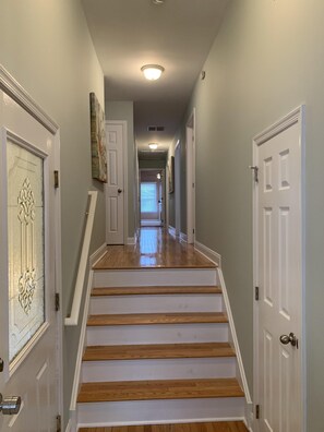 Staircase leads to a spacious hallway with doors and a framed artwork.