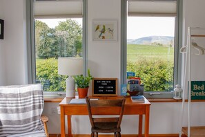 Enjoy a peaceful retreat with a desk and chair positioned in front of a window overlooking a lush landscape.