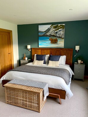 Cozy retreat with a large bed, dark green accent wall, and a coastal scene above.