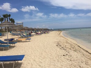 A beach with sun loungers and umbrellas, a lifeguard tower, and clear blue skies. - 2 Bed Flat - Sleeps 4 - Pool - Parking - Wifi (Xylofagou)