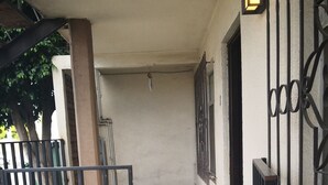 Ein Korridor mit gefliestem Boden, einem Metallgitter und einer Wand mit Fenster und Tür.