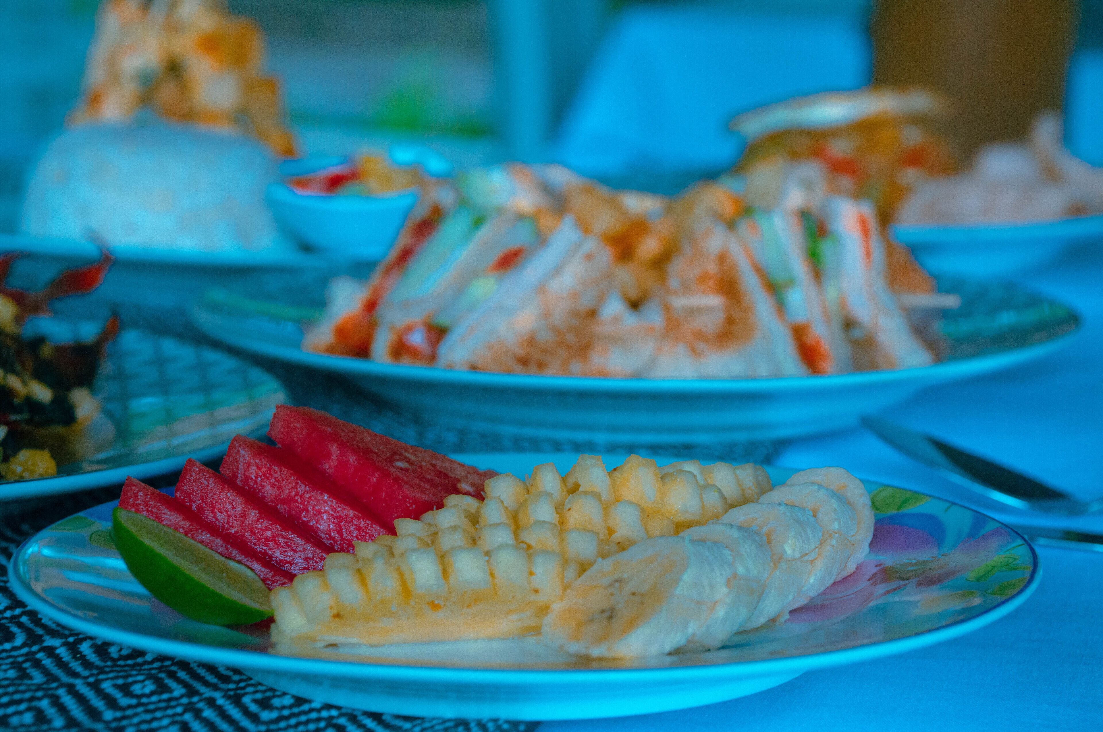 A table with various food items including sandwiches, fruits, and a bowl of soup.