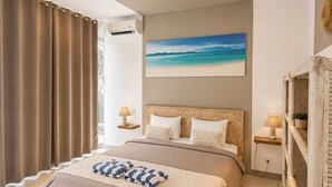 A bedroom with a bed, a painting of a beach, a bedside table, and a lamp. - Samalas Boutique Hotel resort & Private Pool Villas (Gili Meno)