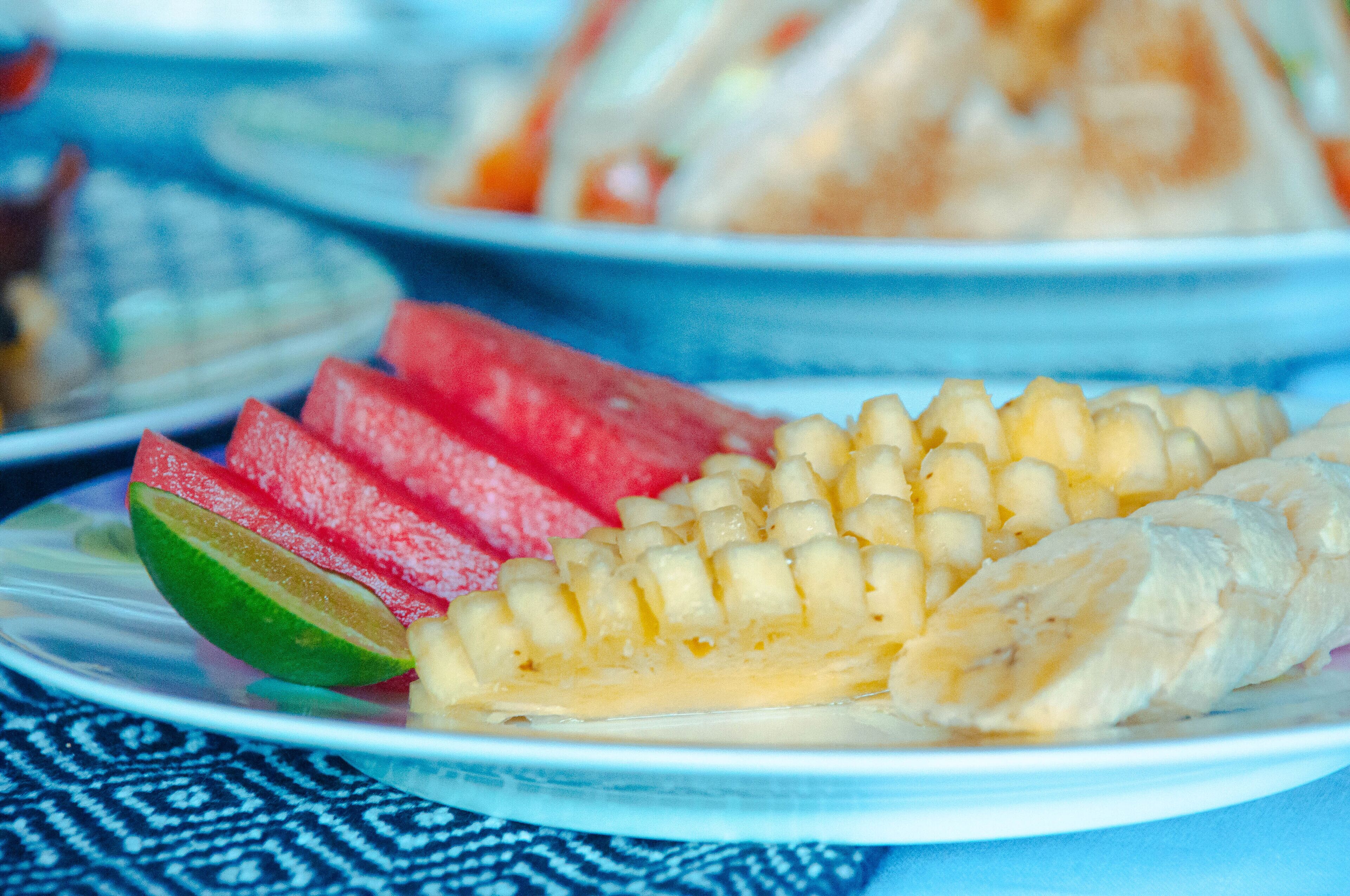 Un plato con sandía en rodajas, lima y banana.