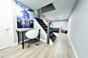 Un espacio de oficina moderno con un escritorio, una silla y una escalera que lleva a una zona en altura.