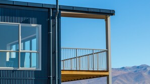 A modern building with a large window and a balcony overlooking a mountainous landscape.