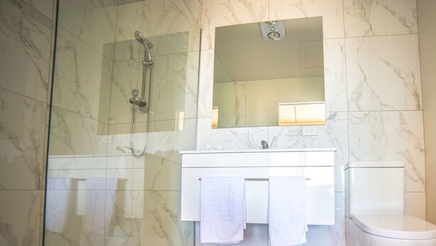A modern bathroom with a glass-enclosed shower, a white sink, and a toilet. - Pukaki Air Lodge (Pukaki)