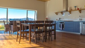 A modern kitchen with a wooden ceiling, large windows, and a view of the mountains.
