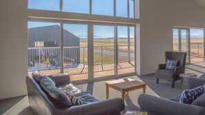 A spacious living room with large windows, a wooden deck, and a view of a distant landscape. - Pukaki Air Lodge (Pukaki)