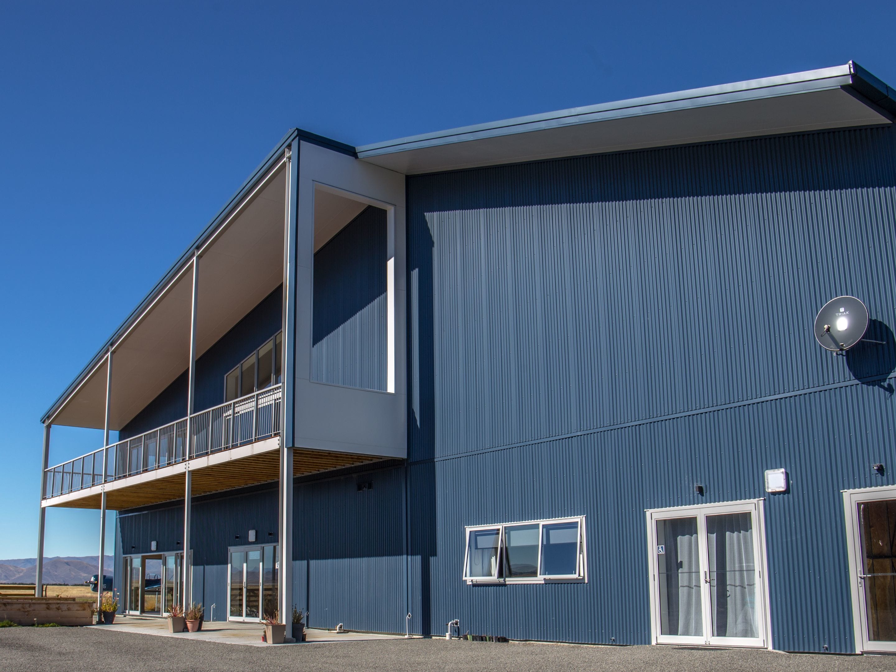A modern building with a flat roof, large windows, and a balcony.