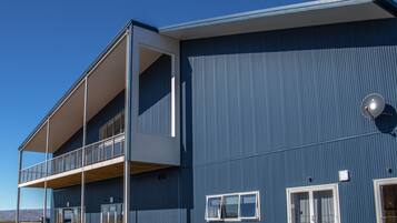 A modern building with a flat roof, large windows, and a balcony.