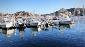 A marina with multiple boats docked, a clear sky, and buildings in the background. - Stunning 2br/2 KING Beds / Spectacular View & Best Location - Expansive Balcony  (Cabo San Lucas)