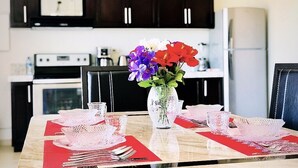 A dining table set with red placemats, white glassware, and a vase with flowers. - Stunning 2br/2 KING Beds / Spectacular View & Best Location - Expansive Balcony  (Cabo San Lucas)