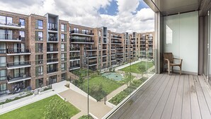 Un moderno edificio de apartamentos con varios balcones, un jardín en la azotea y vistas del entorno.