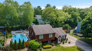 Ein zweistöckiges Haus mit Swimmingpool, umgeben von einem gepflegten Rasen und Bäumen.