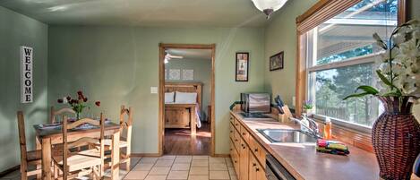 A kitchen with wooden cabinets, a sink, and a dining area with a table and chairs.