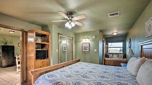 A bedroom with a large bed, wooden wardrobe, a ceiling fan, and a window with a view.
