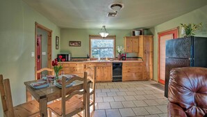 A kitchen with wooden cabinets, a refrigerator, and a dining table with chairs.