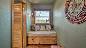 A cozy room with a built-in bed, a window with a view, and a decorative mirror.