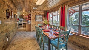 Uma cabana de madeira com área de refeições, cozinha e janelas amplas.