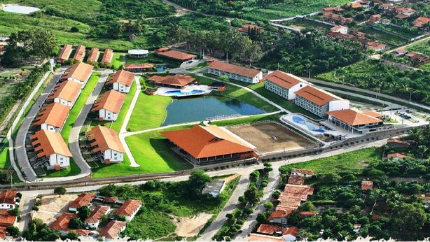Een luchiebeeld van een resort met meerdere gebouwen, een zwembad en een tennisbaan.