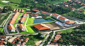 Vue aérienne d’un complexe hôtelier comprenant plusieurs bâtiments, une piscine et un court de tennis.