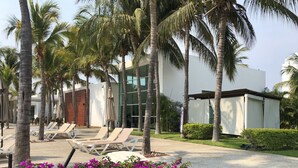 Un resort con palmeras, sillas de descanso y una zona de piscina.