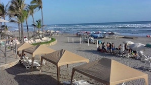 Una playa con tumbonas, sombrillas y palmeras.
