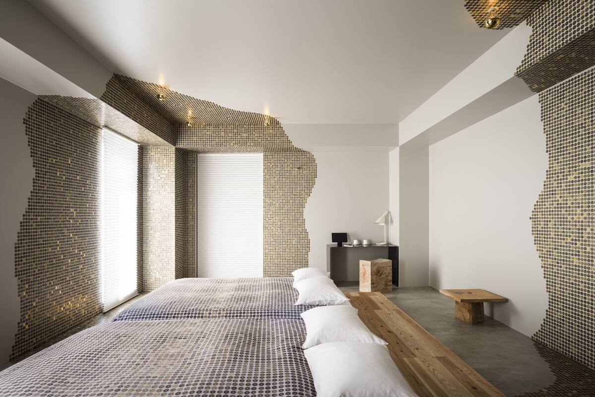A modern bedroom with a large bed, a wooden bench, and a small table.