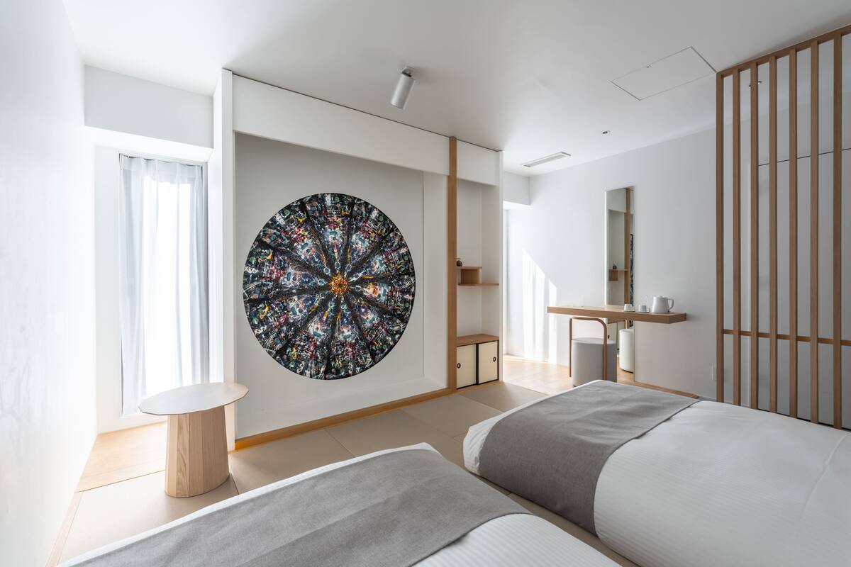 A modern bedroom with a large circular artwork on the wall, a bed, a small round table, and a wooden partition.