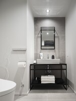 A modern bathroom with a white toilet, a black vanity with a mirror, and a towel rack.