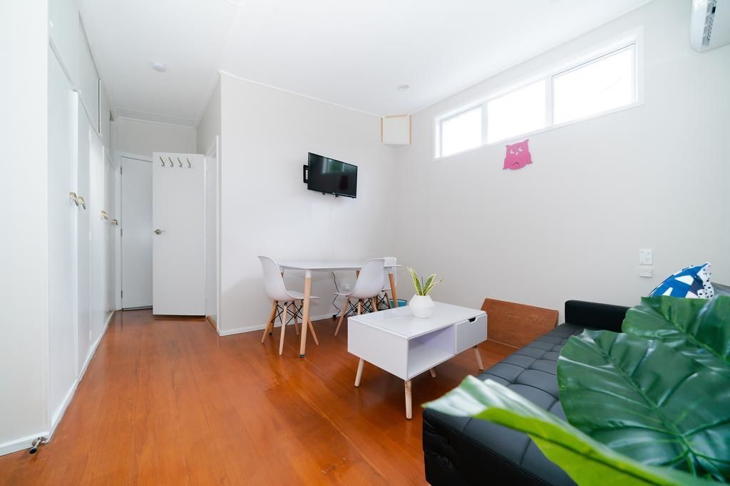 A modern living room with a white sofa, a coffee table, and a TV mounted on the wall.
