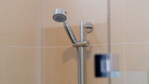 A showerhead with a handheld attachment, mounted on a wall with a grid pattern. - Takapuna Central Spacious & New Home (Auckland)
