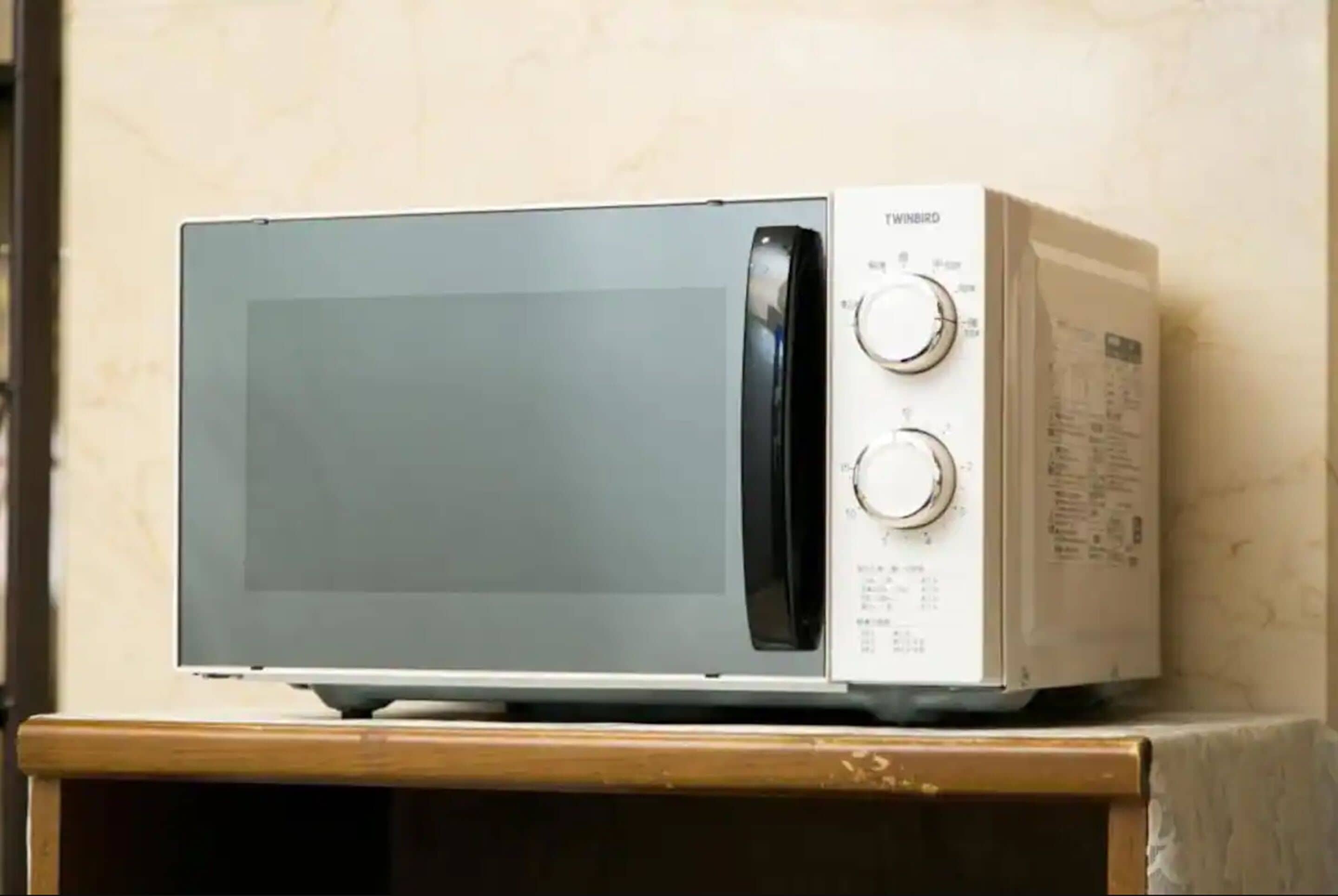 A white TVINBIRD microwave oven on a wooden surface.