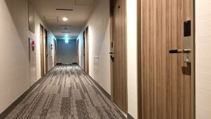 Un pasillo de hotel con pisos alfombrados, puertas de madera y una lámpara en el techo.