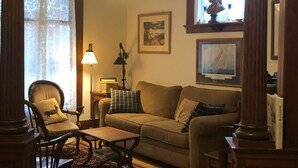 A living room with a wooden floor, a sofa, a chair, a table, and a lamp.