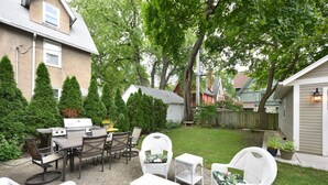 A patio area with outdoor furniture, a grill, and a lawn.