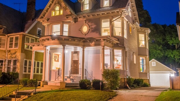 A Victorian-style house with a prominent front porch, multiple windows, and a garage.