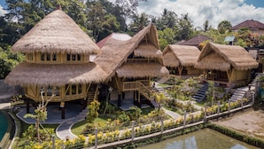 Ein Resort mit strohgedeckten Hütten, einem Schwimmbad und einem angelegten Garten.