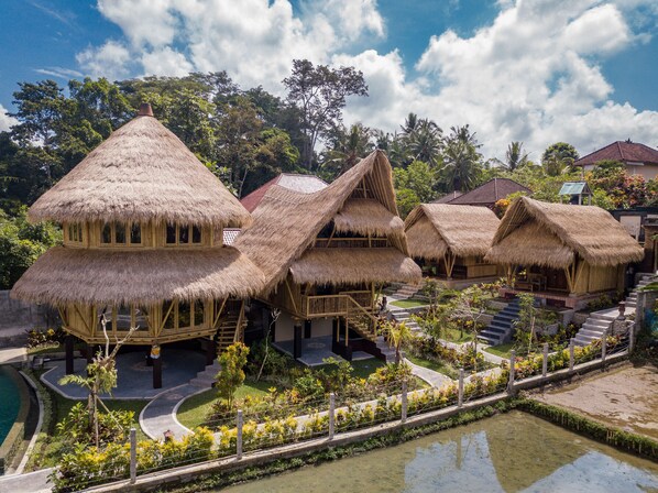 Un resort con cabañas de techo de paja, piscina y jardín ajardinado.