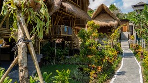 Ein tropisches Resort mit strohgedeckten Hütten, einem gepflasterten Weg und üppiger Vegetation.